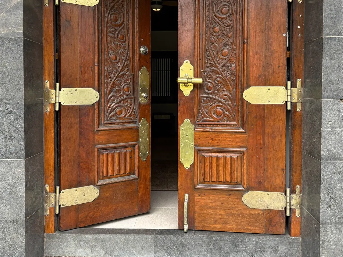 Carved Balinese teak door with new brass hinges in a stone doorway